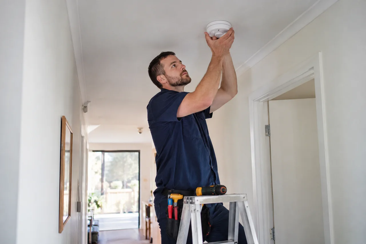 an electrician fitting a ceiling smoke alarm